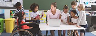 School kids using digital tablet while teacher interacting with students at school