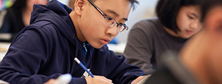 Asian boy studies in elementary school classroom with classmates