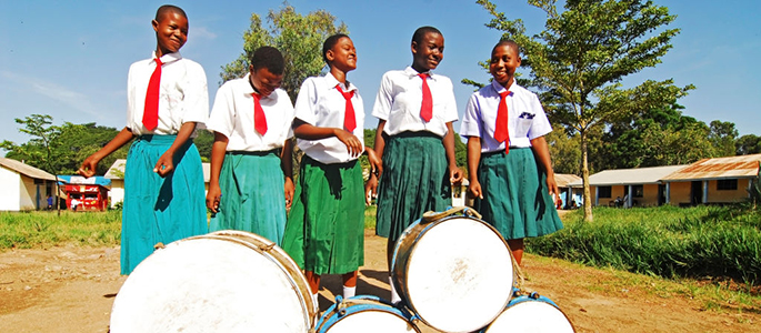 Tanzania, Mwanza, schoolchildren dancing and playing drum in schoolyard